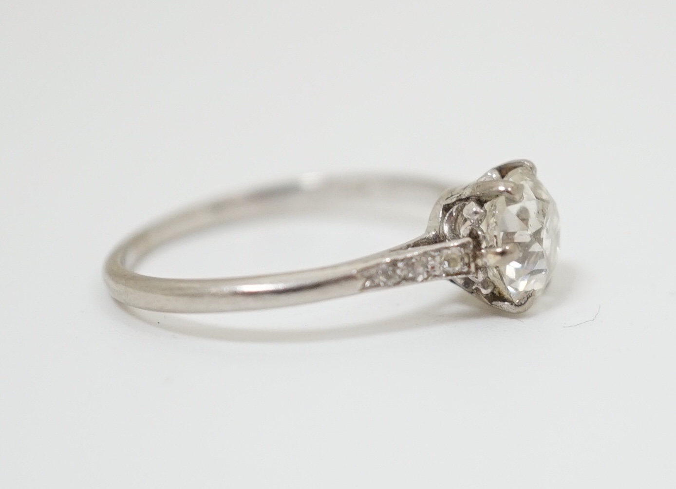 A platinum and single stone diamond ring, with diamond chip set shoulders